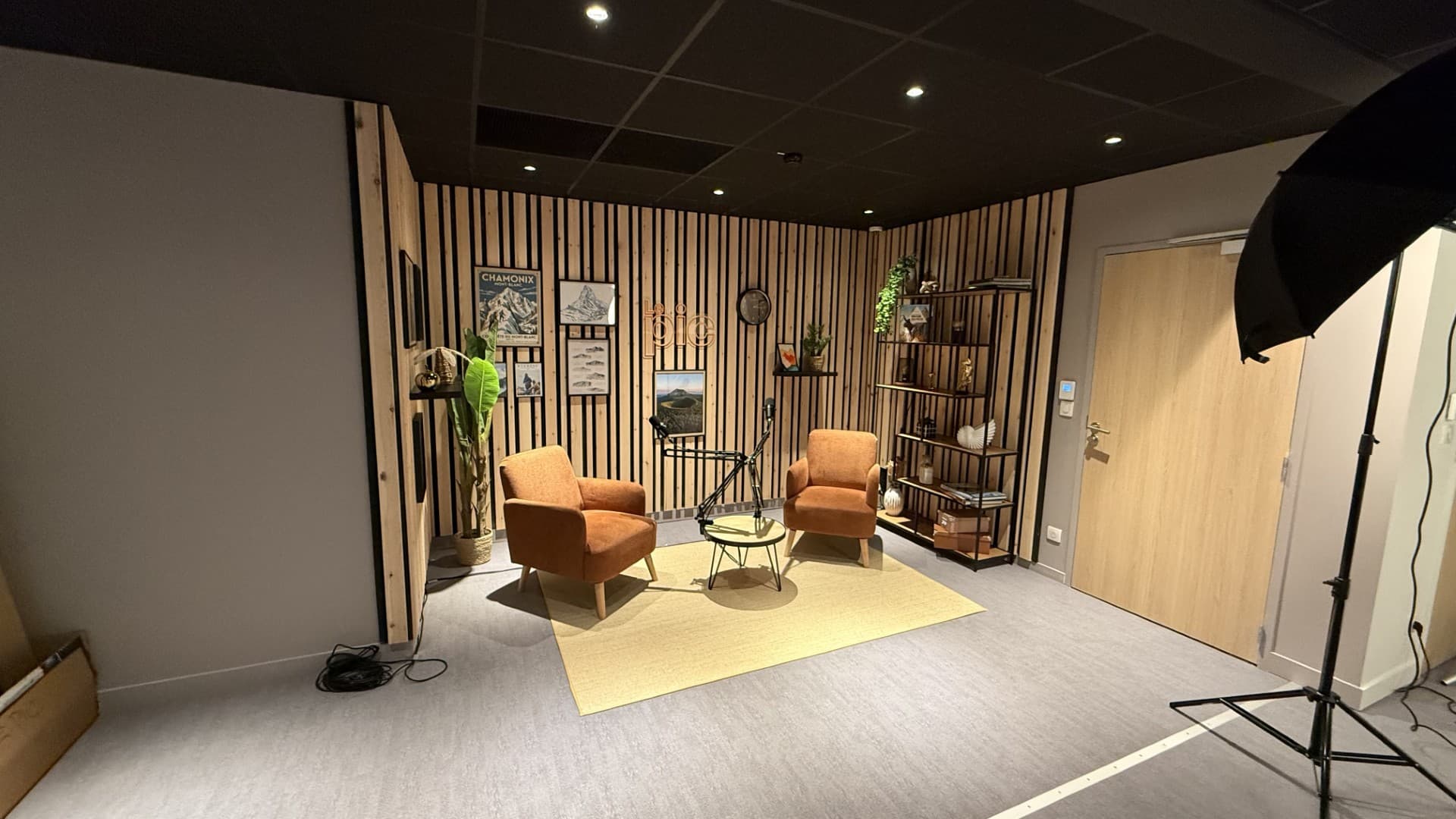 Le plateau du studio photo, vidéo et podcast du PIC à Clermont-Ferrand, deux fauteuils face caméra, micros sur perche et mur en tasseaux de bois